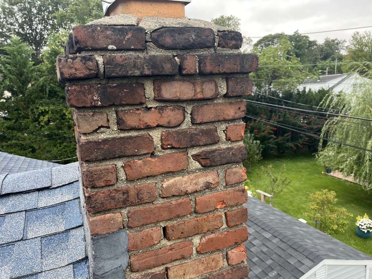 Deteriorated chimney with spalling brick and missing mortar joints on Long Island home