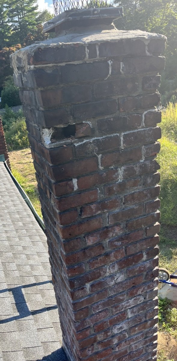 Tall chimney with crumbling crown and missing chimney cap needing rebuild