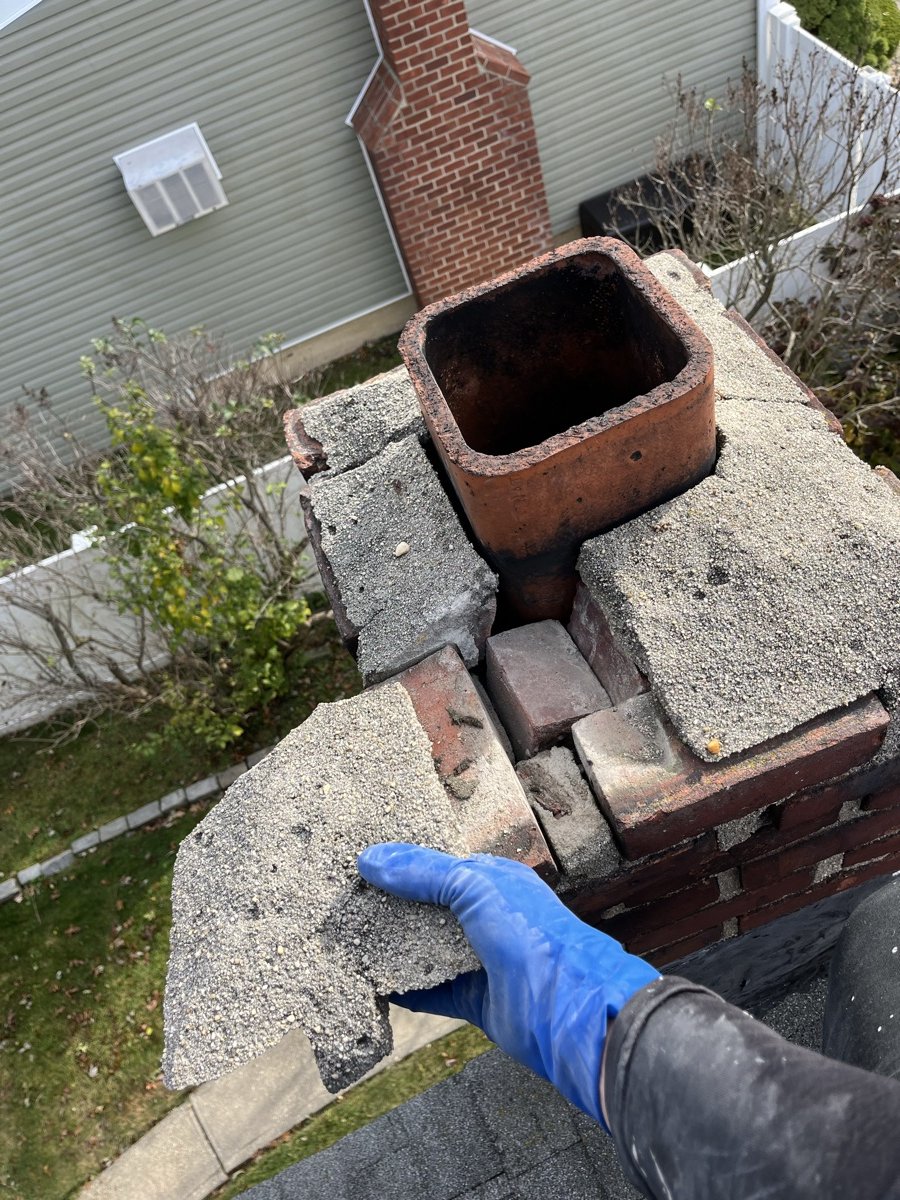Technician removing deteriorated crown pieces from damaged chimney top