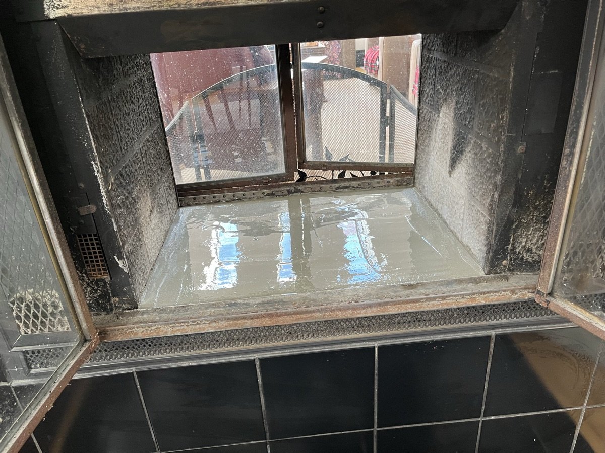 Water pooling inside fireplace firebox indicating chimney leak