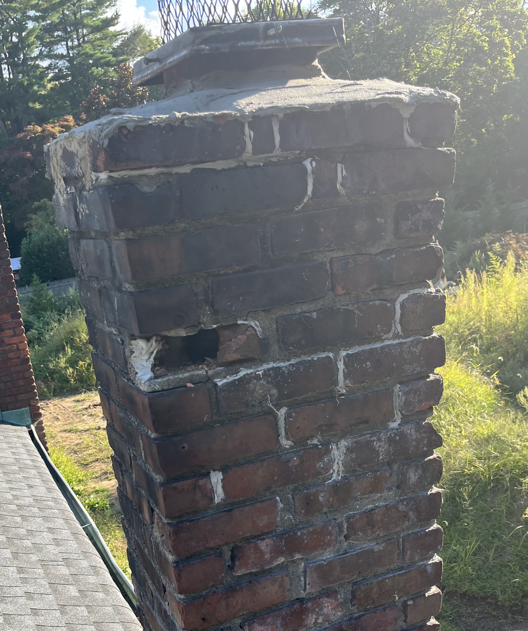 Chimney with missing bricks and deteriorated mortar joints needing repointing